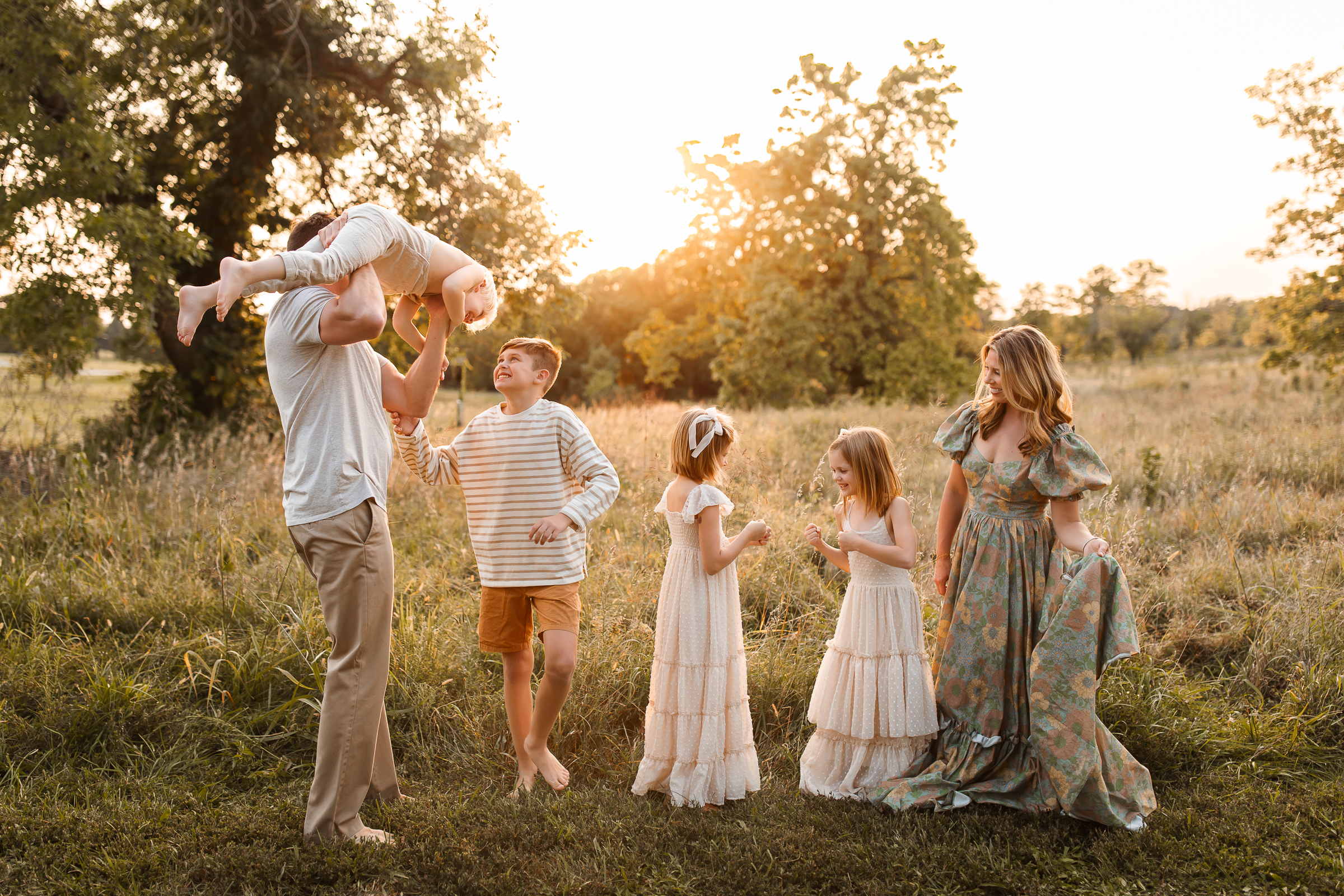 family playing in a field at sunset